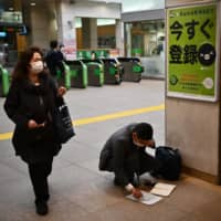 Travelers are seen wearing face masks at a train station in Tokyo on Tuesday. | AFP-JIJI