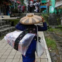 A Baduy woman carries food supplies at Kanekes village, which is closed for visitors amid the spread of the coronavirus, in Lebak, Banten, Indonesia, on Tuesday.  | REUTERS