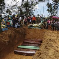 Relatives mourn at the site of a mass burial at the Nossa Senhora Aparecida cemetery, in Manaus, Amazonas state, Brazil, on April 21. The cemetery is carrying out burials in common graves due to the large number of deaths from COVID-19 disease. | AP