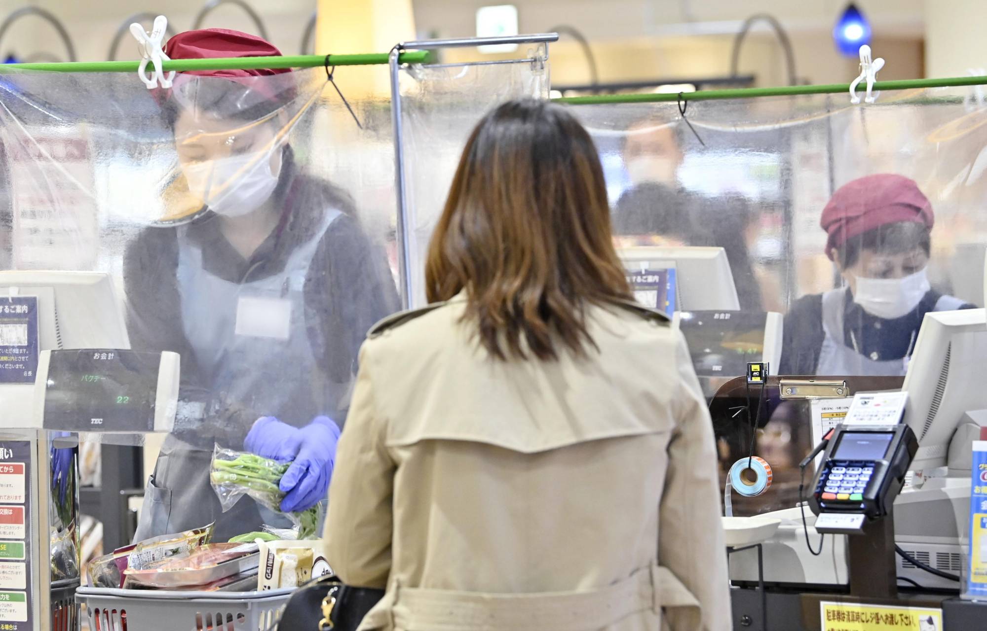 Cashiers work behind plastic drapes at a supermarket in Nagoya on April 24 amid the new coronavirus pandemic. | KYODO