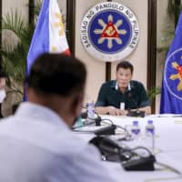 Philippine President Rodrigo Duterte (right) talks to Cabinet officials during a meeting in Manila on Monday. | MALACANANG PRESIDENTIAL PHOTOGRAPHERS DIVISION / VIA AP