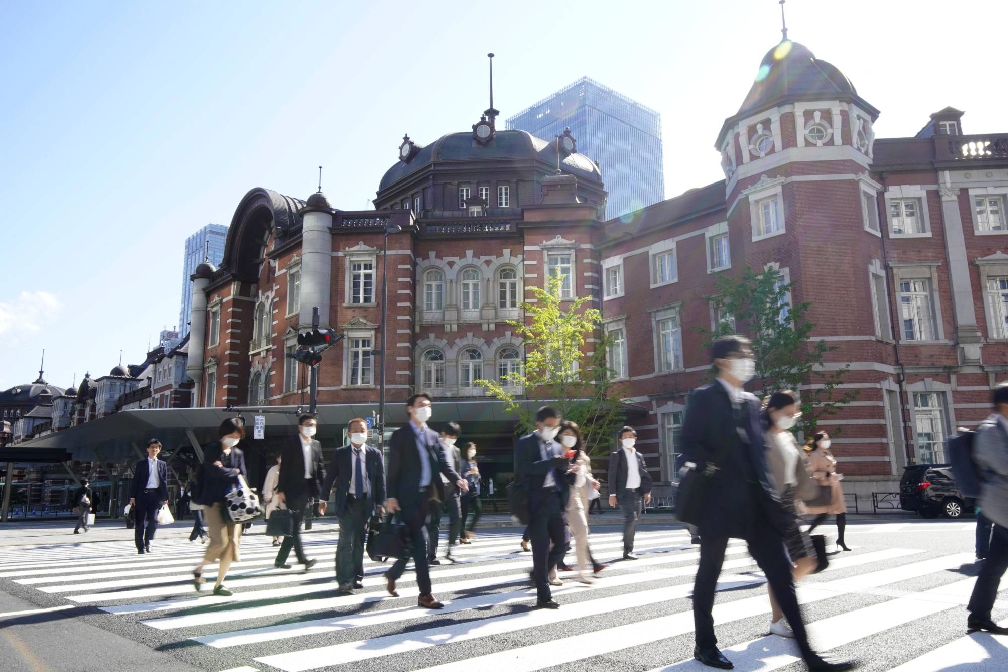 Commuters wearing face masks walk in front of Tokyo Station on Thursday morning, the first workday after the Golden Week holiday. | KYODO