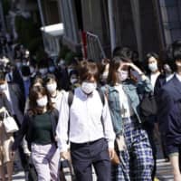 People wear masks as they commute during the morning rush hour Thursday in Tokyo. | AP