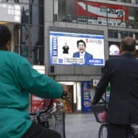 A screen shows Prime Minister Shinzo Abe explaining the extension of a nationwide state of emergency due to the coronavirus pandemic on May 4 in Osaka\'s Dotonbori district. | KYODO