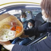 Customers pick up flowers for Mother\'s Day at a drive-thru service in Kawasaki on Saturday. | KYODO
