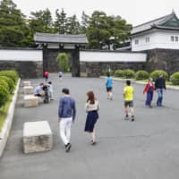 People take a walk near the Imperial Palace in Tokyo on Saturday under an extended state of emergency over the coronavirus pandemic. | TOKYO