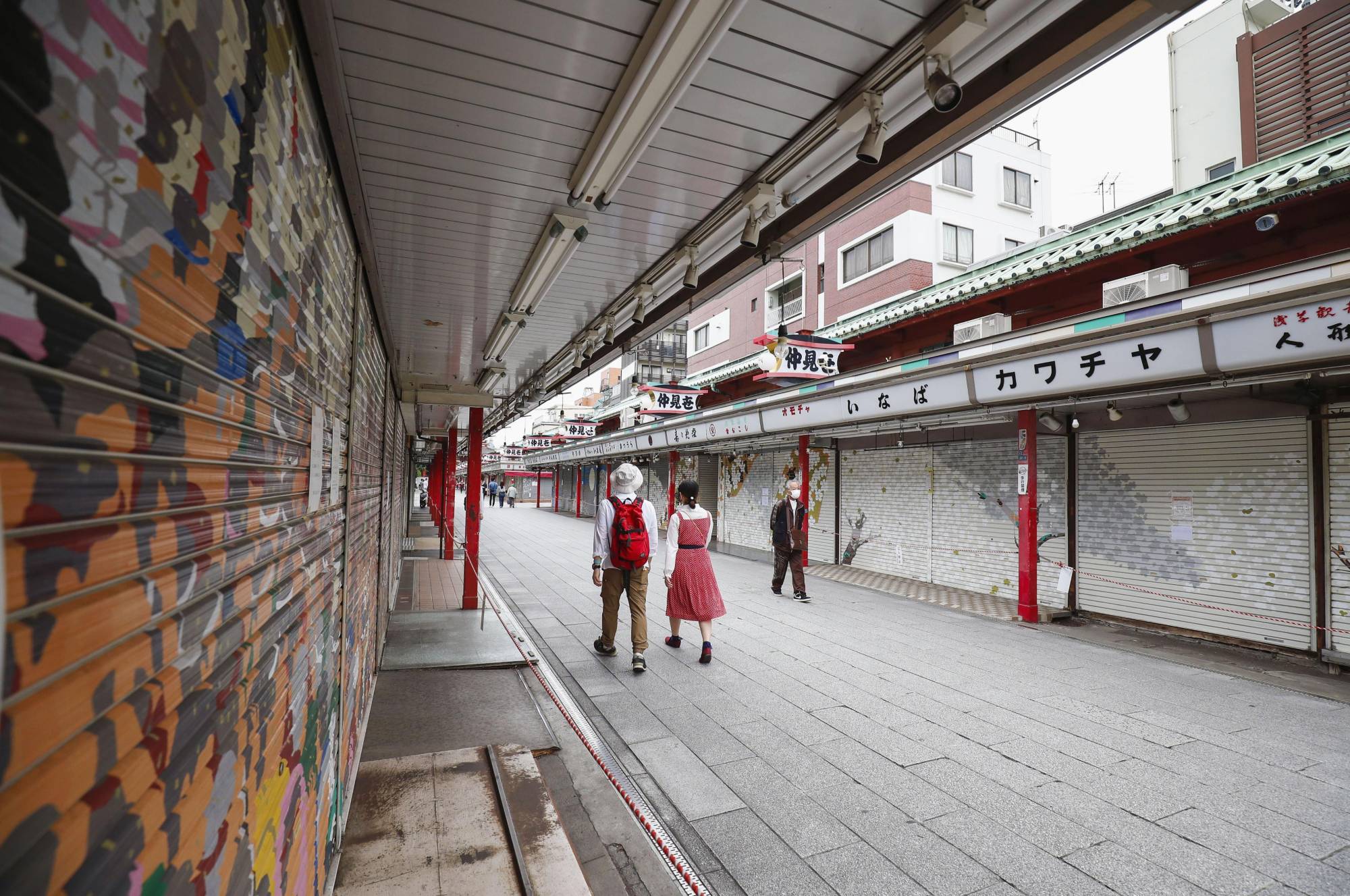People walk past shuttered stores in Tokyo's Asakusa tourist area on Saturday amid an extended nationwide state of emergency over the coronavirus pandemic. | KYODO