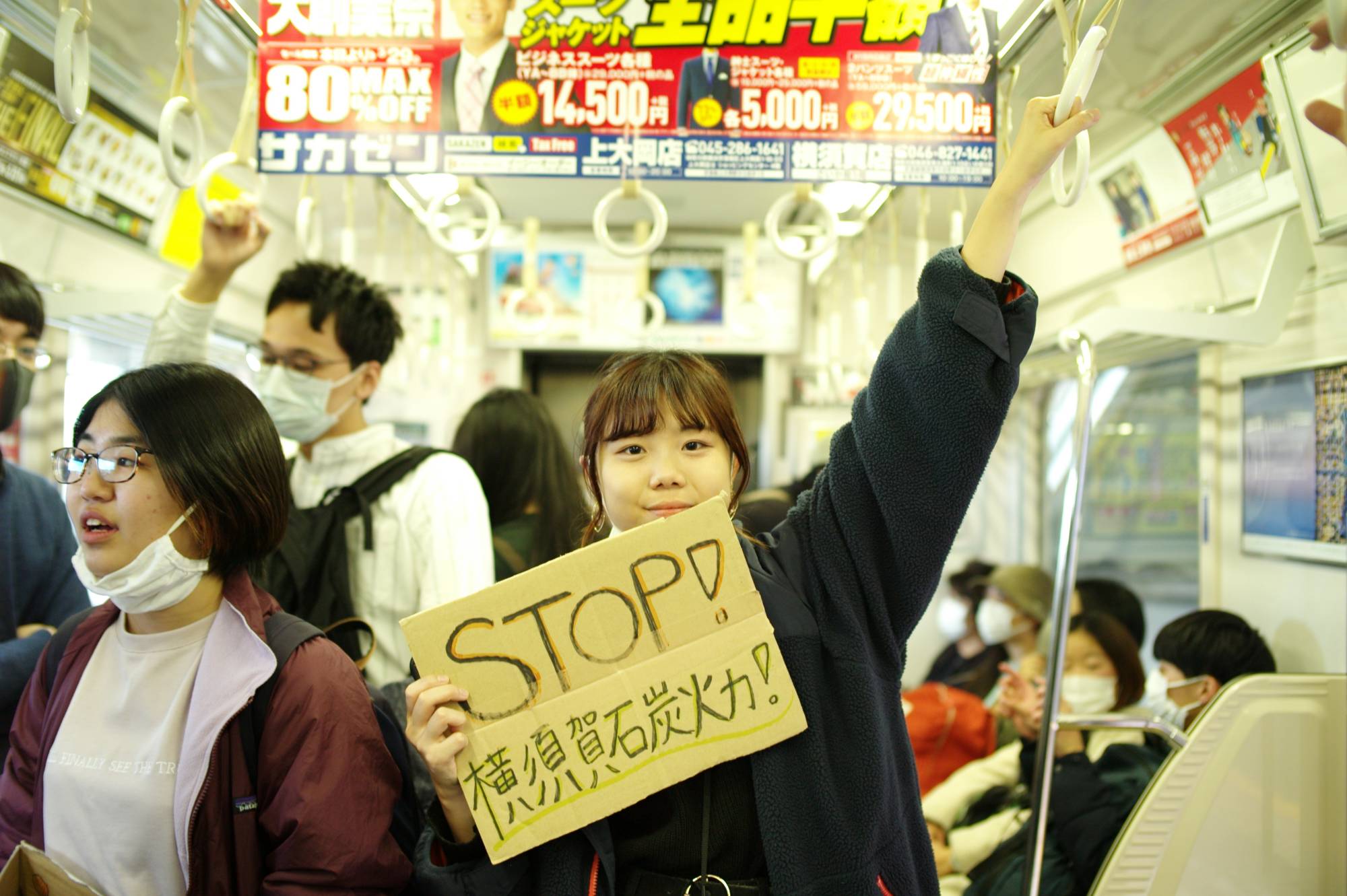 Yui Tanaka, 20, holds a sign that reads 'Stop coal power in Yokosuka!' on her way to a protest at the construction site of a new coal power plant in the city in March. | RYUSEI TAKAHASHI 
