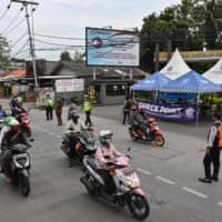 Motorists commute past a checkpoint during a partial lockdown to curb the spread of COVID-19 in Jakarta on Monday. | AFP