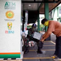 A man gets rice out of an automated distributor in Jakarta on May 4. | REUTERS
