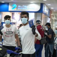 Right of passage: Young Kuwaitis arrive home from Jordan wearing face masks and quarantine tracking bracelets. | REUTERS