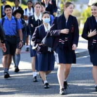 Students arrive for the first day of face-to-face schooling after a period of learning from home due to coronavirus precautions in Brisbane, Australia, on Monday. Australia\'s second-most populous state, Victoria, will resume in-person teaching May 27, weeks earlier than expected. | DAN PELED / VIA REUTERS