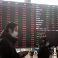 People wearing protective masks walk past an electronic stock board at the Shanghai Stock Exchange in Shanghai. Given the coronavirus pandemic, market participants are redrawing their long-term trading strategies.
 | BLOOMBERG