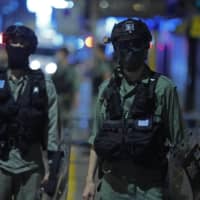 Police officers stand guard Monday. More than 200 people were arrested during anti-government protests the same day. | AP
