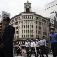 People wearing face masks to help curb the spread of the coronavirus walk at Tokyo\'s Ginza shopping district on Tuesday. | AP