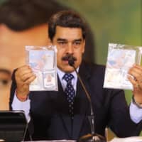 Venezuelan President Nicolas Maduro shows the passports of two U.S. citizens arrested by security forces during a meeting with international media May 6. | VENEZUELAN PRESIDENCY / VIA AFP-JIJI