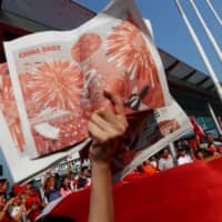 A China supporter holds up copies of the China Daily at Harbour City, Hong Kong, during China\'s National Day on Oct. 1 last year.  | REUTERS 