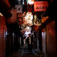 A man walks along a Tokyo street lined with restaurants and bars that are closed due to the coronavirus outbreak. Japan\'s nighttime entertainment business, premised on a male-dominated society and where men are mainly entertained by women, may gradually diminish in the post-pandemic era. | REUTERS