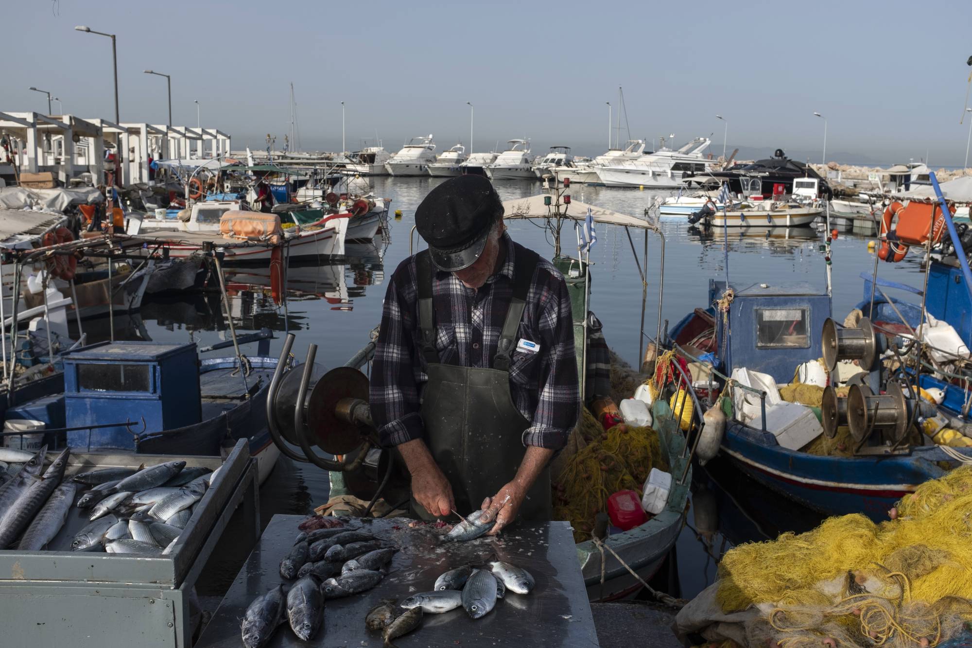 A fisherman cleans fish at a near Athens on Thursday. The European Union’s executive arm pushed for a continent-wide revival of tourism with a series of policy recommendations for EU countries as they loosen lockdowns triggered by the coronavirus pandemic. | BLOOMBERG