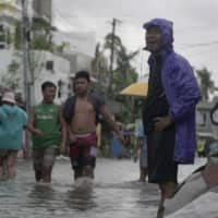 Residents wade along a flooded village caused by Typhoon Vongfong as it passed by Sorsogon province, eastern Philippines, on Friday. | AP