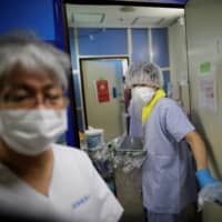 Medical workers wear protective face masks as they work in the intensive care unit for coronavirus patients at St. Marianna Medical University Hospital in Kawasaki on May 4. | REUTERS