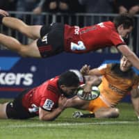 The Crusaders\' Codie Taylor (below left) dives across the line to score a try as teammate George Bridge flies above him during the Super Rugby final between the Crusaders and the Jaguares on July 6, 2019, in Christchurch, New Zealand. | AP