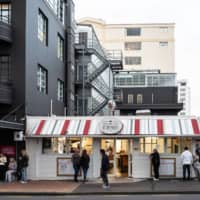 Customers maintain social distancing while they wait outside a fast food restaurant during a staged exit from New Zealand\'s coronavirus lockdown in Wellington on Thursday. | BLOOMBERG