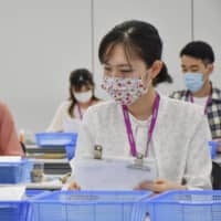 Cabin crew trainees of Peach Aviation Ltd. on Monday check forms submitted to the Izumisano Municipal Government at the firm\'s office in Izumisano, Osaka Prefecture. | KYODO