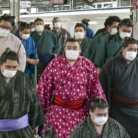 Sumo wrestlers wearing protective face masks arrive at Shin-Osaka Station in February ahead of the Spring Grand Sumo Tournament in Osaka. | KYODO