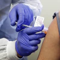 A man receives a shot in a clinical trial of a potential vaccine for COVID-19 in Seattle on March 16. On Monday, Massachusetts-based Moderna Therapeutics Inc. announced that a vaccine it is developing generated antibodies similar to those seen in people who have recovered from COVID-19 in a study of volunteers who were given either a low or medium dose.  | AP