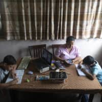 A mother helps her children with online homework in Caracas earlier this month. | AP