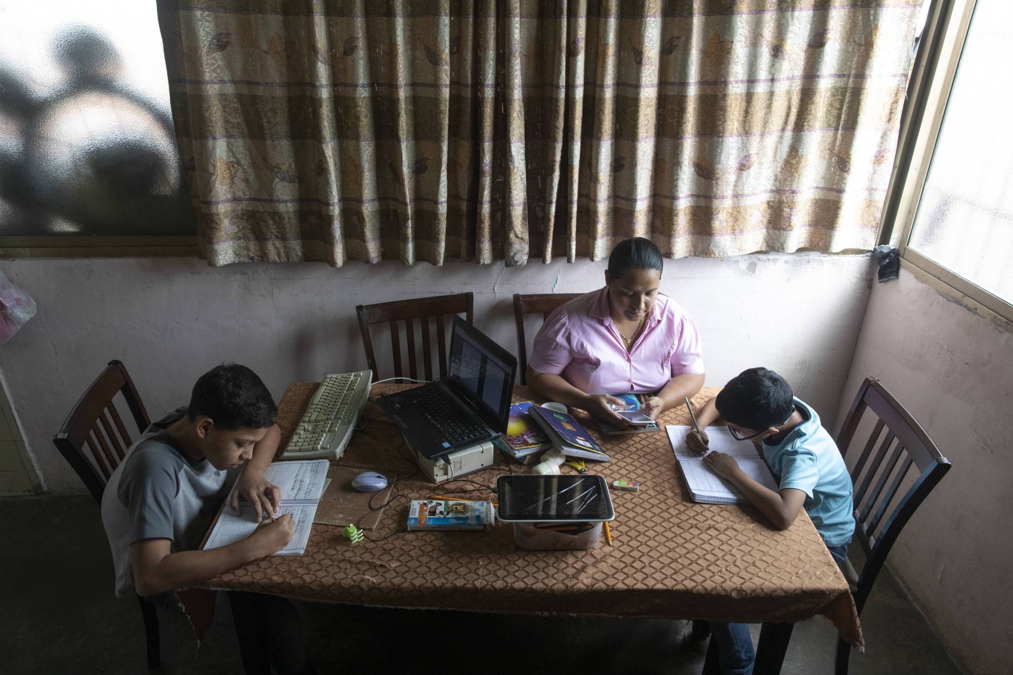 A mother helps her children with online homework in Caracas earlier this month. | AP