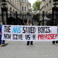 Nurses who work at central London hospitals hold a protest outside Downing Street in central London on May 13 to call for improved conditions and pay. Since 2015, the U.K.’s National Health Service has endured massive budget cuts. | AFP-JIJI