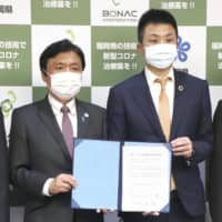 Bonac Corp. CEO Hirotake Hayashi (right) and Fukuoka Gov. Hiroshi Ogawa pose for photos after signing an agreement to work together to develop a drug to treat the novel coronavirus on Monday. | KYODO