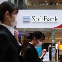 Pedestrians walk past a SoftBank mobile phone store in Tokyo on Monday. | AFP-JIJI