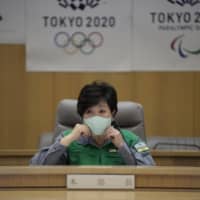 Tokyo Gov. Yuriko Koike adjusts her mask during a meeting of the metropolitan government\'s coronavirus task force on Friday following her announcement of the city\'s plan to reopen the capital after the possible lifting of the state of emergency on Monday. | RYUSEI TAKAHASHI
