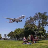 A family watches a China Airlines plane landing at Los Angeles International Airport at the start of the Memorial Day holiday weekend on Friday. | AFP-JIJI