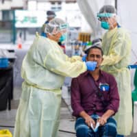 Medical staff test a migrant worker at the Avery Lodge for COVID-19 in Singapore on May 15. | SINGAPORE MINISTRY OF MANPOWER / VIA AFP-JIJI