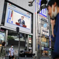 A large screen on a building shows a live broadcasting of Prime Minister Shinzo Abe\'s news conference on Japan\'s response to the coronavirus outbreak in Tokyo\'s Shinjuku district on May 14. Japan’s coronavirus state of emergency was coming to an end, but Abe’s political troubles may be just beginning. | REUTERS