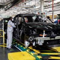 An employee wearing a protective face mask works on the Nissan Micra hybrid automobile assembly line at the Renault SA factory in Flins, France, on May 6. | BLOOMBERG 