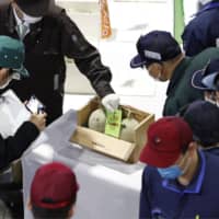 A pair of melons farmed in Yubari, Hokkaido, are auctioned and sold for ¥120,000 on Monday in Sapporo.  | KYODO
