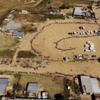 Thousands of people line up to receive food handouts in the Olievenhoutbos township of Midrand, South Africa. The country with the Africa’s most developed economy also has its highest number of infections with more than 22,500. | AP