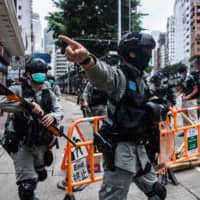 Riot police clear up debris left by protesters attending a pro-democracy rally against a proposed new security law in Hong Kong on Sunday. | AFP-JIJI