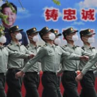 Chinese People\'s Liberation Army soldiers  march past a banner depicting Chinese President Xi Jinping inside the Tiananmen Gate in Beijing during a plenary session of China\'s National People\'s Congress at the Great Hall of the People on Monday. | AP