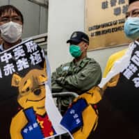 Pro-democracy activists tear a placard of Winnie-the-Pooh, representing Chinese President Xi Jinping, during a protest against proposed new security laws outside the Chinese Liaison Office in Hong Kong on Sunday.  | AFP-JIJI