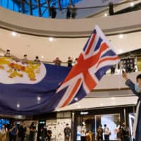 A demonstrator waves a colonial-era Hong Kong flag during a protest at the International Finance Center shopping mall in Hong Kong on Monday.  | BLOOMBERG 
