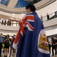 A demonstrator wears a colonial-era Hong Kong flag during a protest against a planned national security law held in the International Finance Center shopping mall in Hong Kong on Monday.  | BLOOMBERG