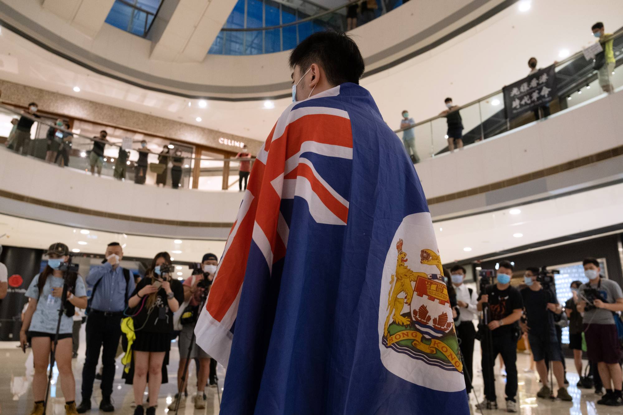 A demonstrator wears a colonial-era Hong Kong flag during a protest against a planned national security law held in the International Finance Center shopping mall in Hong Kong on Monday.  | BLOOMBERG
