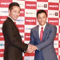 Shinji Shimada poses for photos with guard Yuki Togashi at a news conference last year in Tokyo. | KAZ NAGATSUKA
