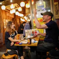 People enjoy drinks at a traditional Japanese-style pub in Tokyo\'s Ueno district on Tuesday, a day after the government lifted the state of emergency for the entire nation. | REUTERS